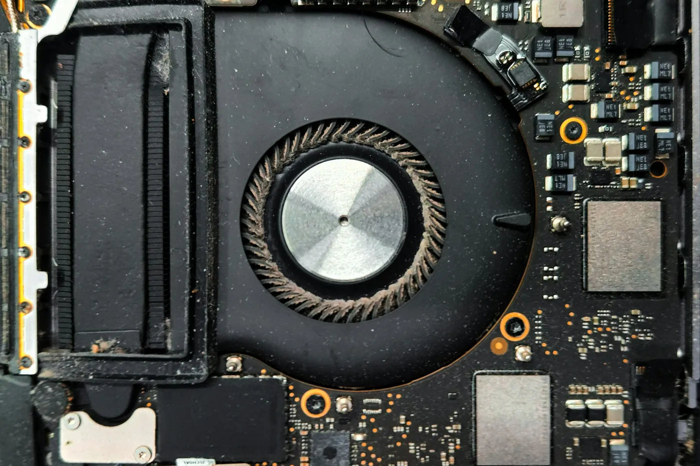 Close de um cooler de notebook com acúmulo visível de poeira nas pás
