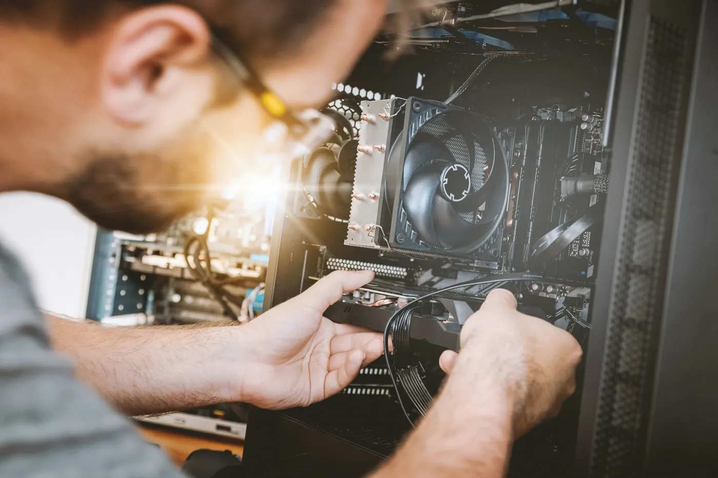 Técnico com chave de fenda trabalhando dentro de um gabinete aberto, ao lado do cooler do processador