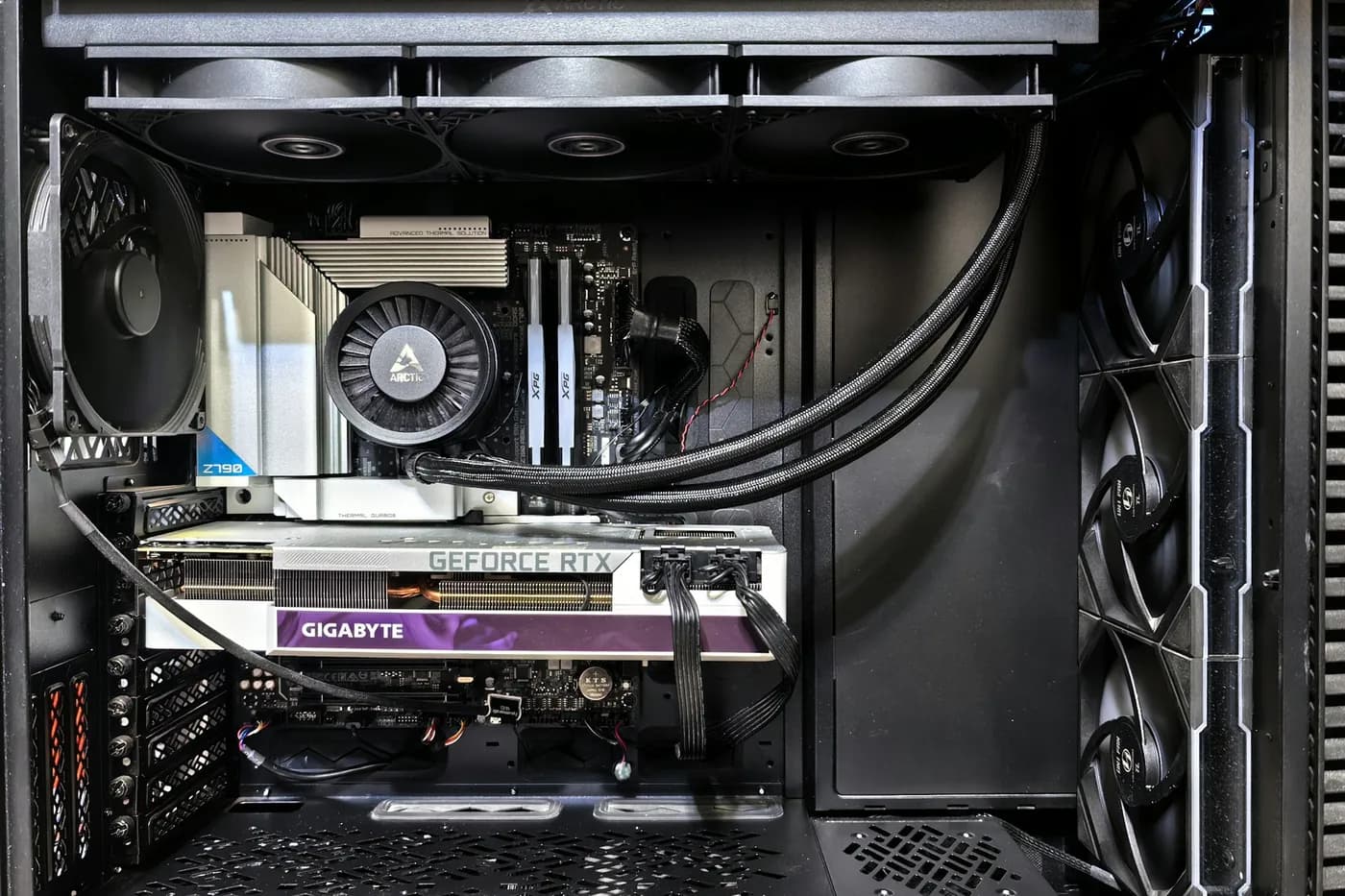 Gabinete aberto com radiador de water cooler no topo, placa de vídeo, cooler de processador e cabos organizados